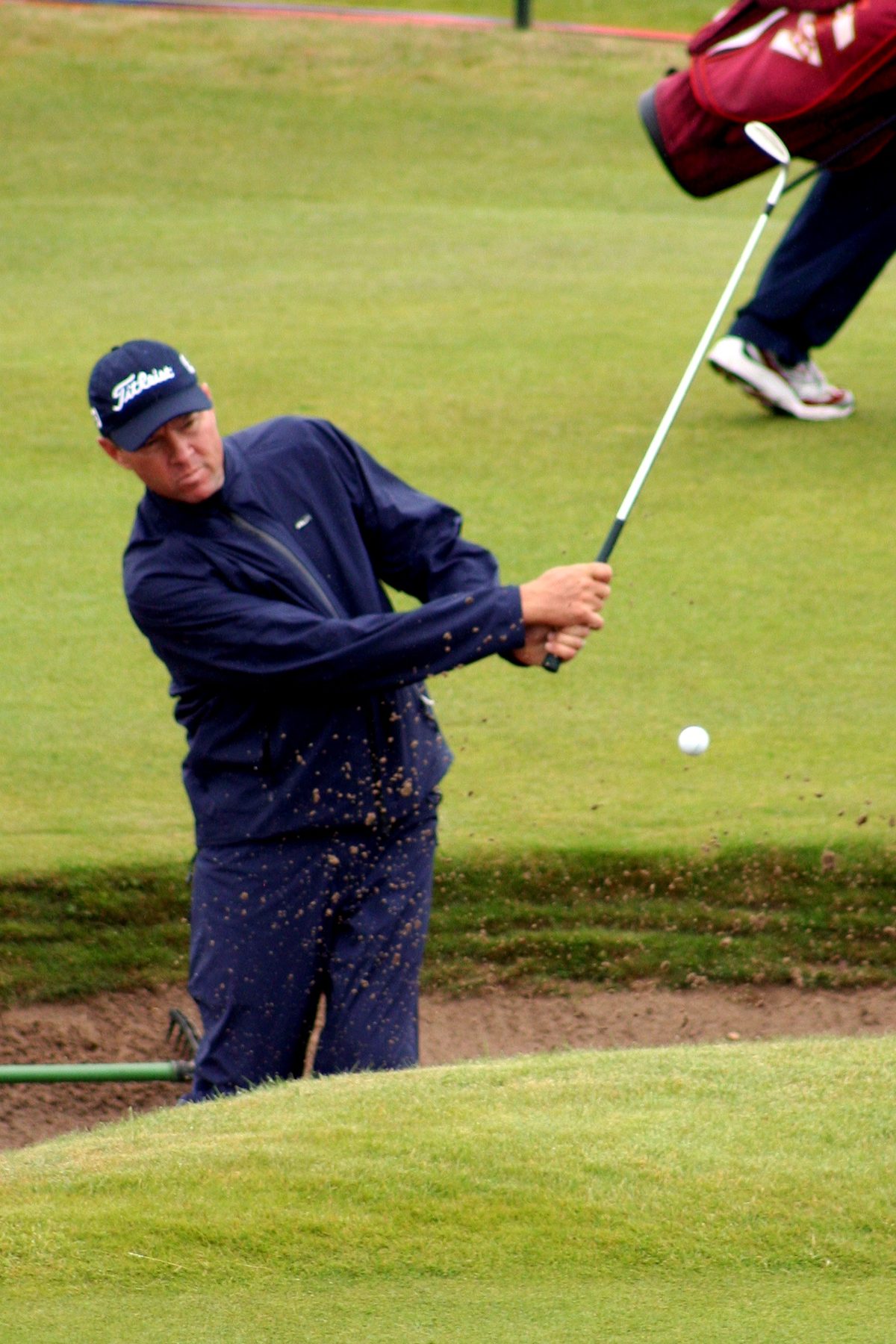 A golfer playing out of a deep revetted pot bunker on a Scottish links course