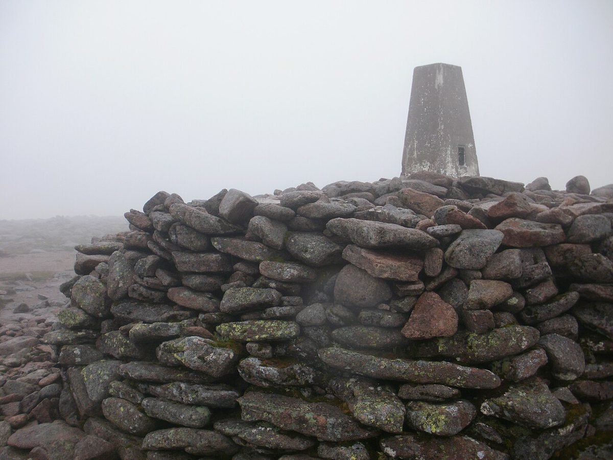 The summit cairn and trig point of Ben Macdui in mist, the highest point of the Cairngorms plateau