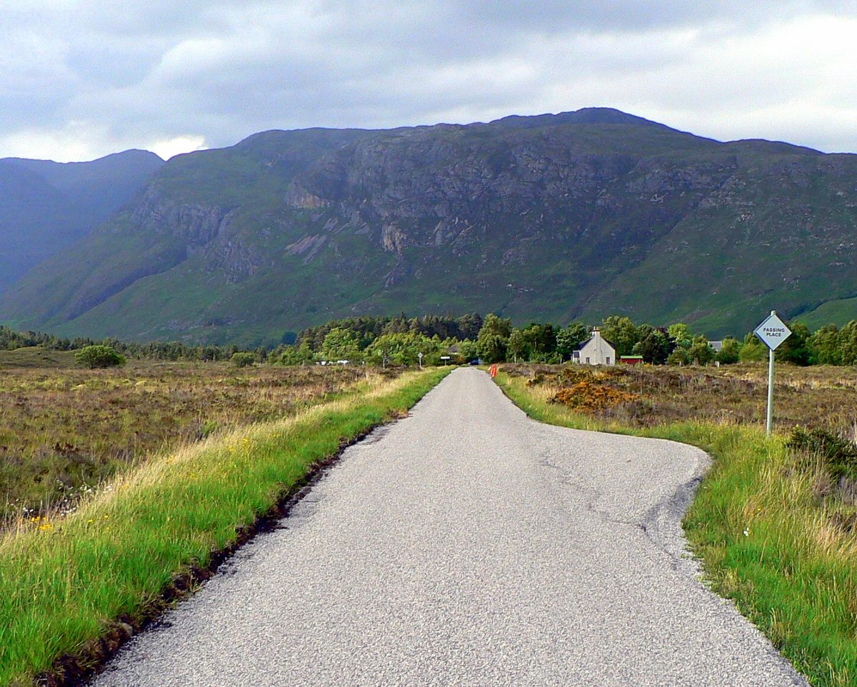 A single-track road with a passing place sign in the Scottish Highlands