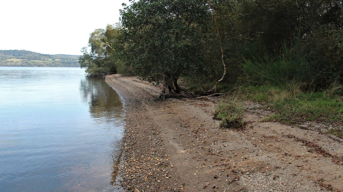 A quiet pebble shore on Loch Lomond looking north towards the Highland hills