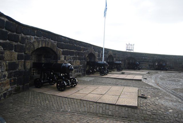 Cannons along the curved Half Moon Battery at Edinburgh Castle beneath a flying saltire
