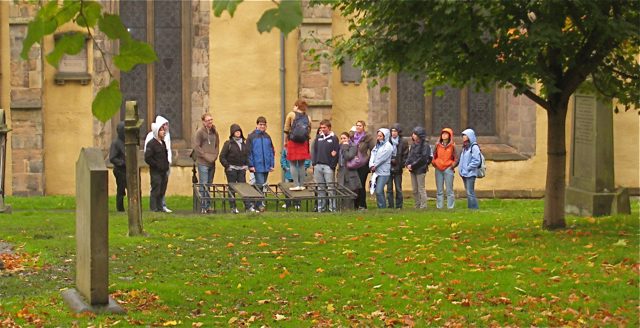 A walking-tour group gathered among the table tombs of Greyfriars Kirkyard in Edinburgh