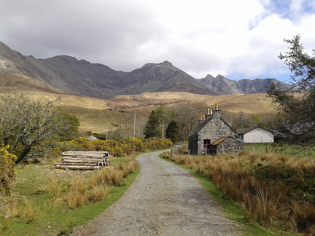 The track down Glen Brittle on the Isle of Skye with the Black Cuillin ridge rising behind a stone cottage