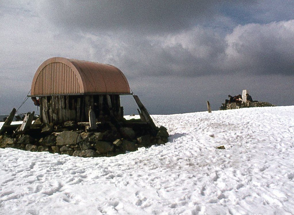 The emergency shelter and summit cairn on the Ben Nevis plateau under late-spring snow