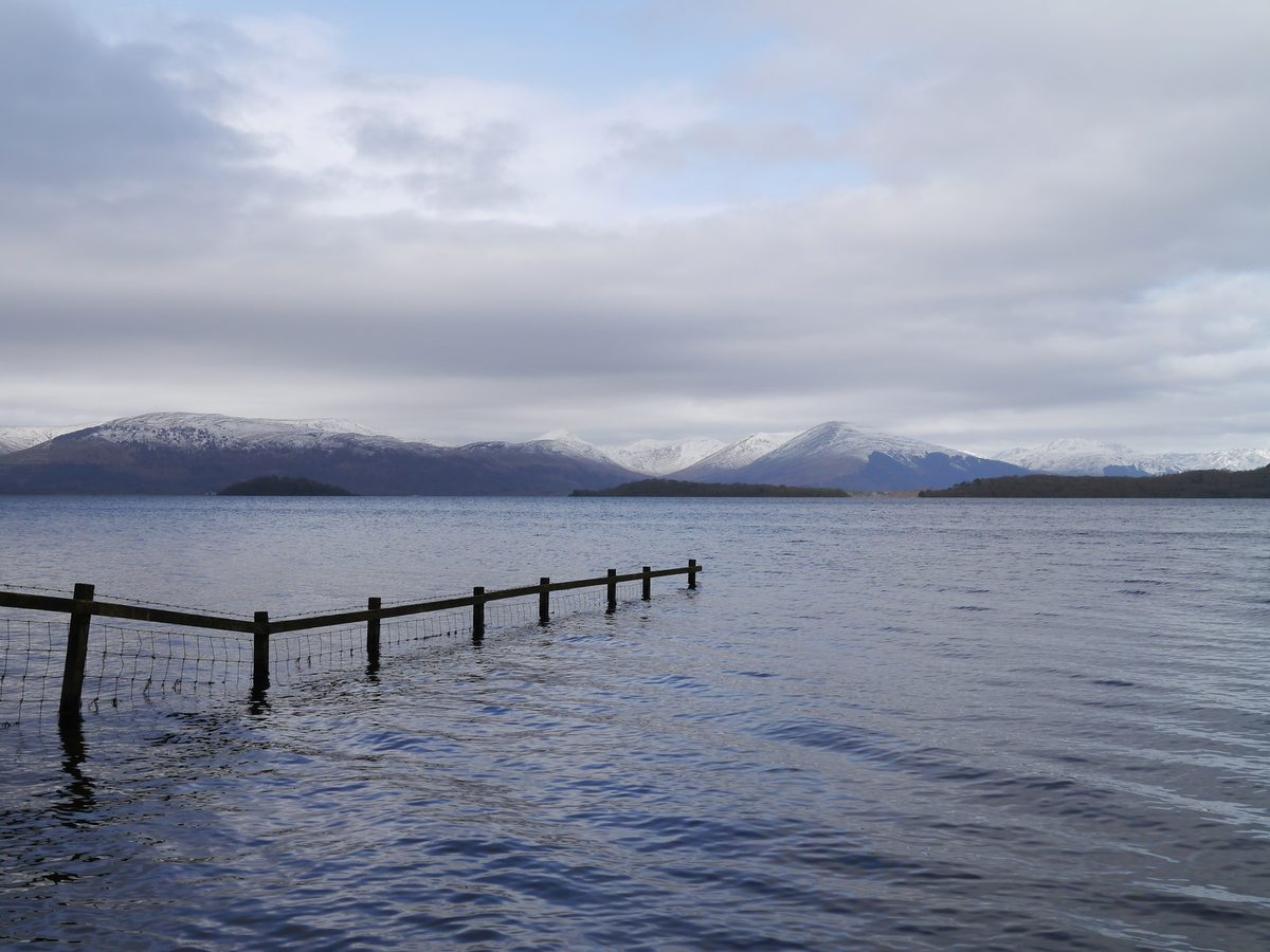 The shore of Loch Lomond with snow on the hills, well outside midge season