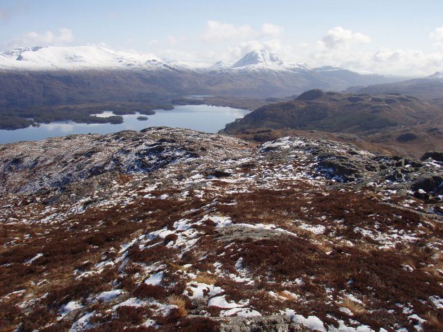 Loch Maree and its wooded islands seen from the hills of Wester Ross, with snow on the Torridon peaks