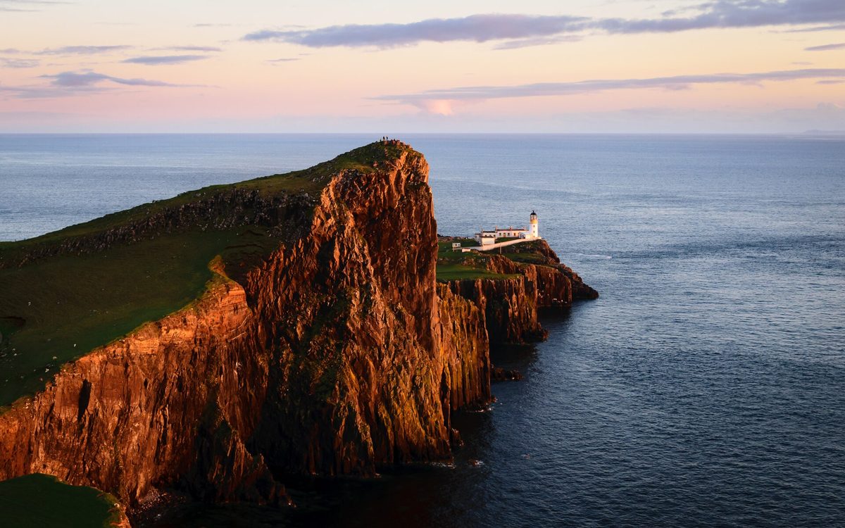 Neist Point lighthouse and the An t-Aigeach headland lit by the setting sun, Isle of Skye