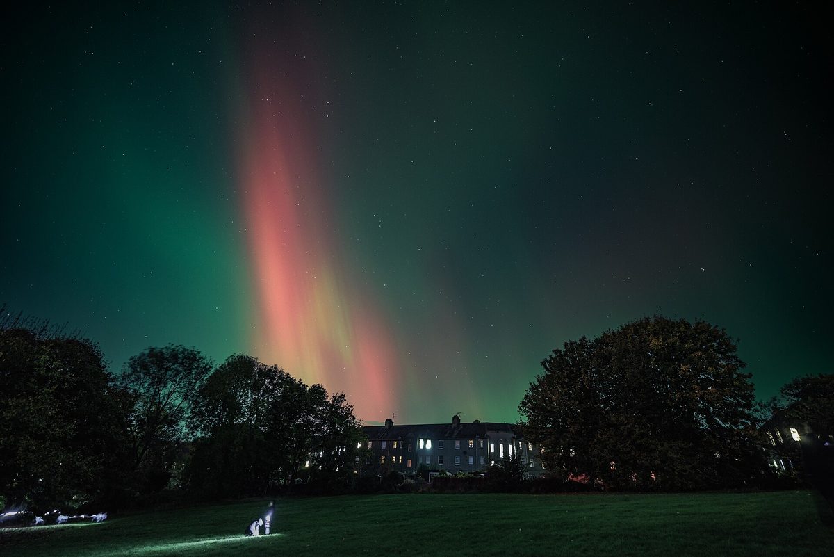 The aurora borealis in green and red over rooftops in Scotland