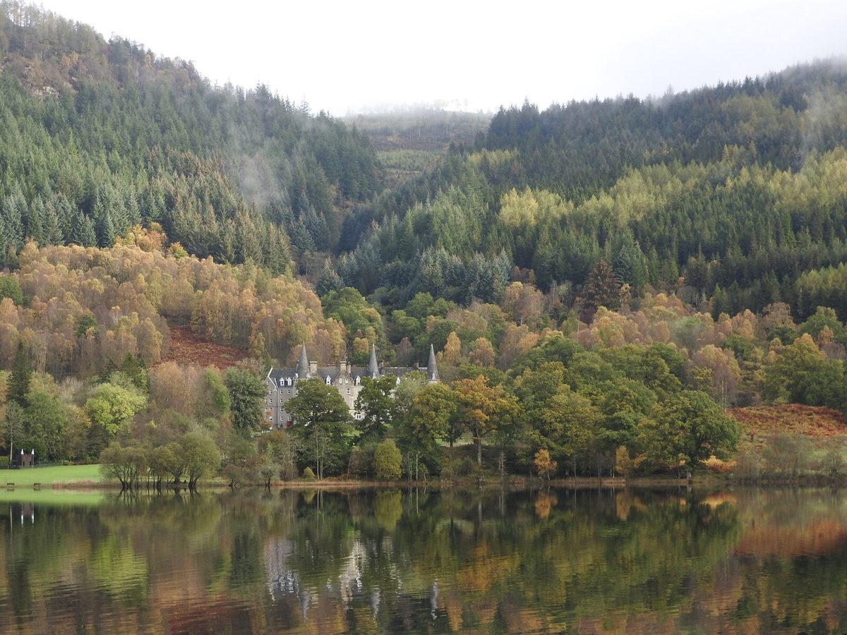 Autumn woodland reflected in Loch Achray in the Trossachs