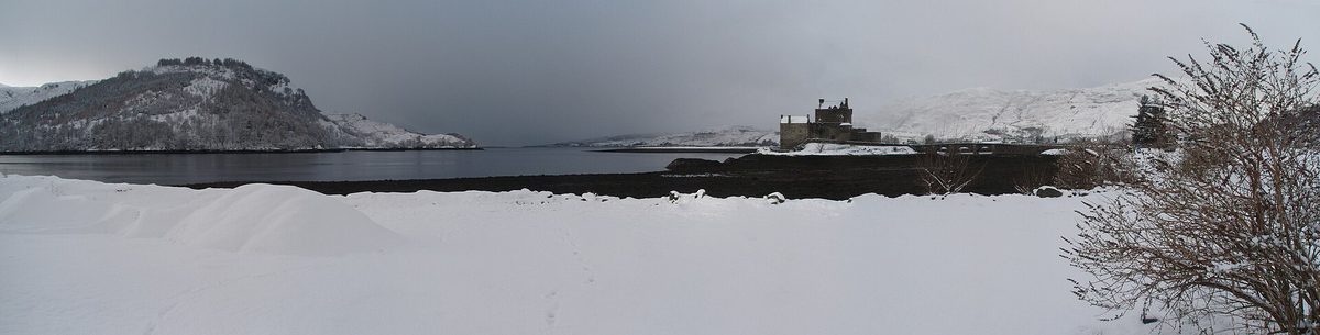 Eilean Donan Castle across a snow-covered shore under a heavy winter sky