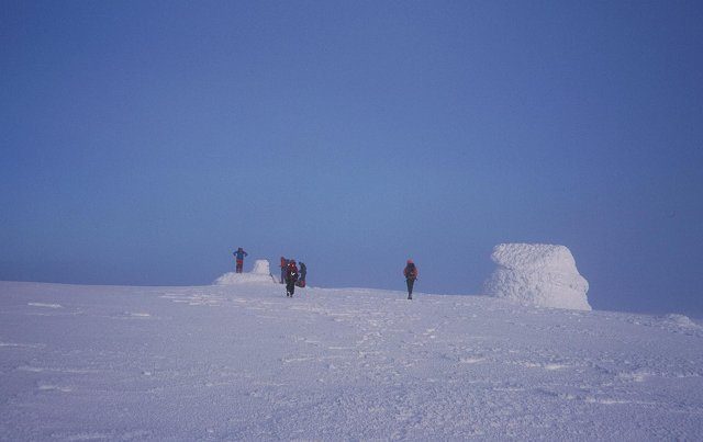 Walkers on the snow-covered summit plateau of Ben Nevis