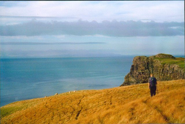 A walker on the clifftop path above Talisker Bay on the Isle of Skye in autumn