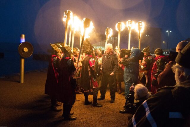 Guizers holding lit torches at Up Helly Aa in Lerwick, one of the most unique things to do in Scotland