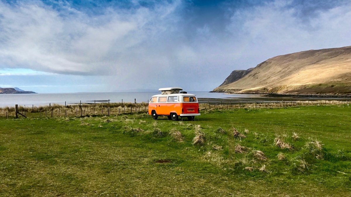 A campervan parked by the shore in the Scottish islands, a popular way to get around Skye