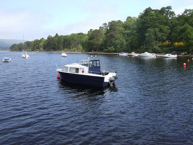 Small boats moored on the wooded shoreline of Loch Ness