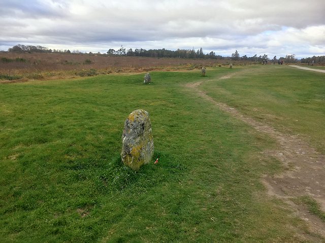 Clan headstones standing in the grass beside the visitor path across Culloden battlefield