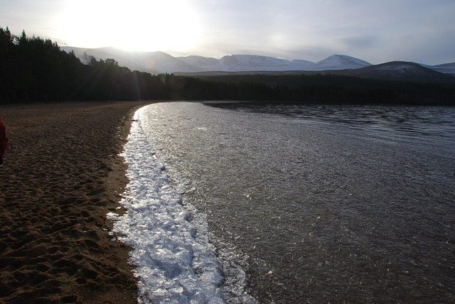 Ice on the shore of Loch Morlich with the snow-covered Cairngorms behind, near Aviemore