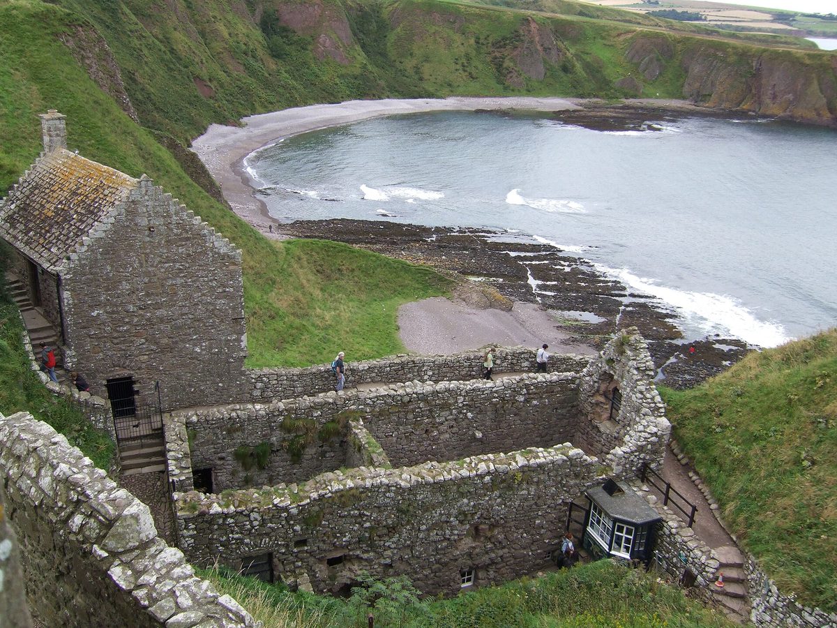 Roofless buildings inside Dunnottar Castle looking down over Castle Haven bay